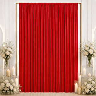 Red velvet event backdrop with white floral arrangements and candles