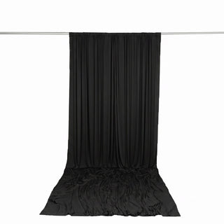 Black draped fabric backdrop hanging on a silver rod, studio display