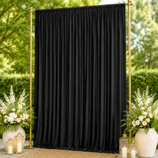 Black draped wedding backdrop with gold frame and floral arrangements outdoors