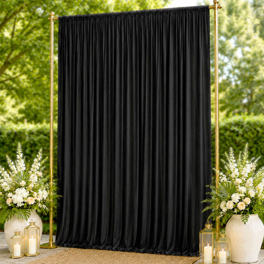 Black draped wedding backdrop with gold frame and floral arrangements outdoors