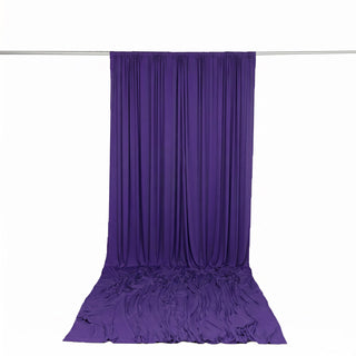 Purple draped fabric backdrop hanging on a rod against white background