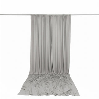 Light gray draped curtain hanging from a silver rod on a white background