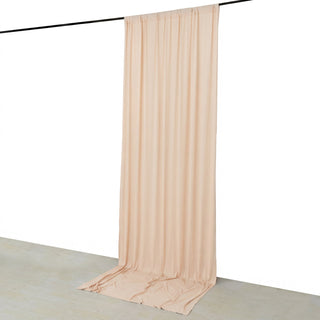 Beige sheer curtain draped on a black rod against a white wall