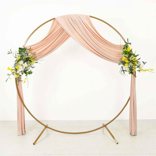 Round gold wedding arch with blush draping and floral arrangements