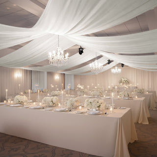 Elegant wedding reception setup with floral centerpieces and soft drapery.