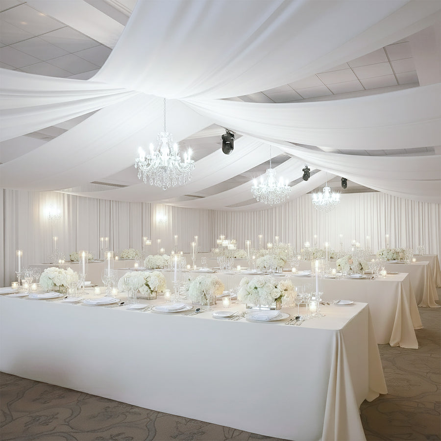 Elegant wedding reception setup with white floral arrangements and chandeliers.