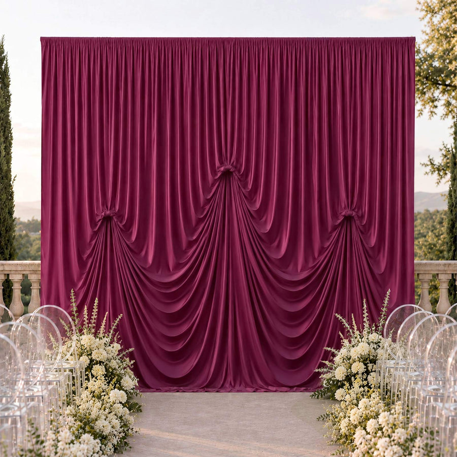 Elegant burgundy draped wedding backdrop with white floral aisle decor