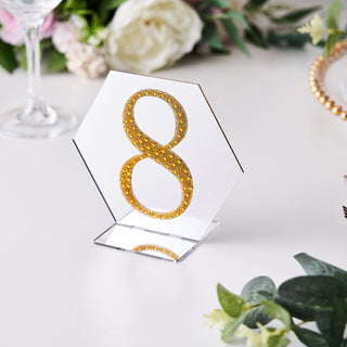 Gold glitter number 8 table sign on clear acrylic base with floral backdrop.