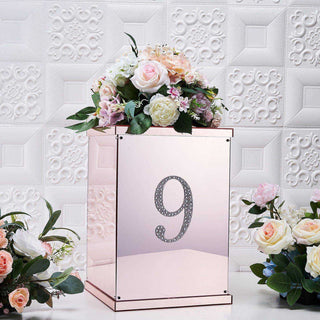 Rose gold flower box with number 9 and floral arrangement on a textured background.