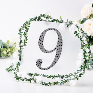 Decorative table number 9 surrounded by greenery and white flowers
