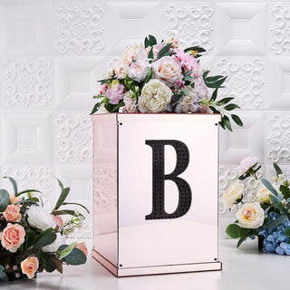 Elegant floral arrangement in a mirrored box with letter "B" decoration.