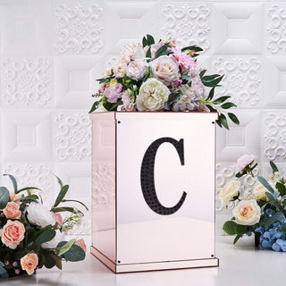 Rose gold floral arrangement box with letter "C" on a textured white background.