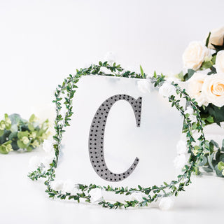 Decorative letter "C" framed by flowers and greenery on a white background.
