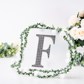 Decorative letter "F" surrounded by flowers and greenery.
