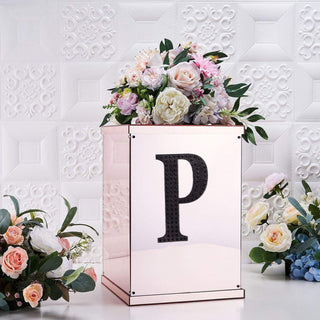 Decorative floral arrangement in a mirrored box with a letter "P" accent.