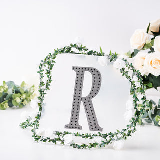 Decorative letter "R" surrounded by floral accents on a white background.