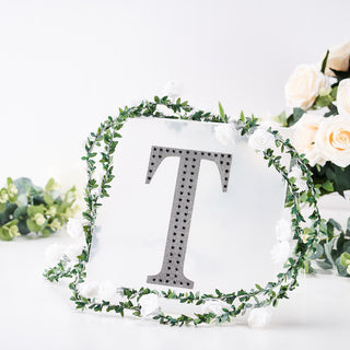 Decorative letter "T" with floral wreath, studio-style isolation shot.