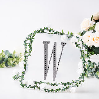 Decorative letter "W" with floral wreath on a white background.
