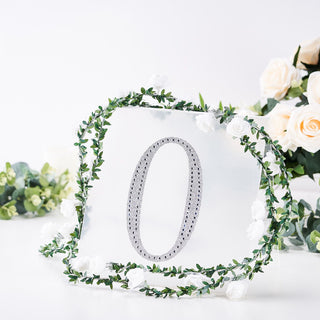 Silver number "0" surrounded by floral decor on a white backdrop.