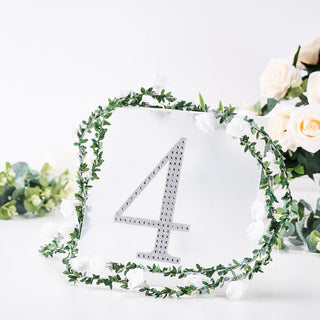 Decorative table number 4 with floral accents and greenery on a white background