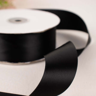 Black satin ribbon on a spool with a loose end visible.