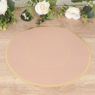 Round blush pink placemat with gold trim on a wooden surface.