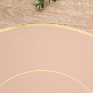 Pink round placemat with gold trim on a wooden surface.