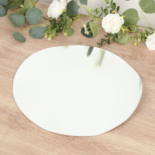 Round mirror placemat on a wooden surface with greenery and flowers.