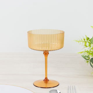 Amber ribbed glass cup on a light surface with greenery.
