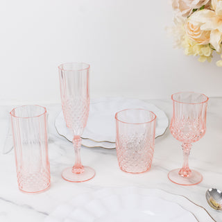 Elegant pink crystal drinkware set on a marble table with white plates.