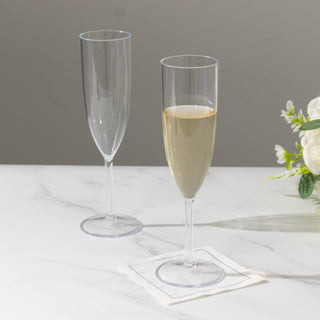 Two elegant champagne flutes on a marble surface, one empty and one filled.