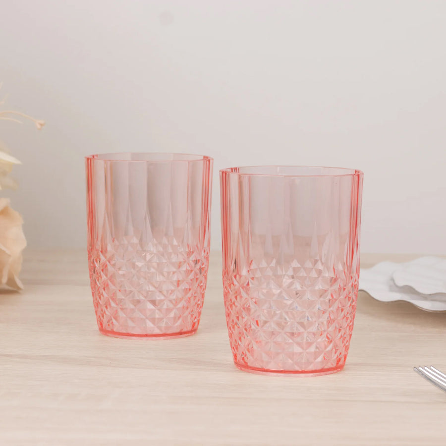 Set of two pink diamond-patterned drinking glasses on a wooden table.