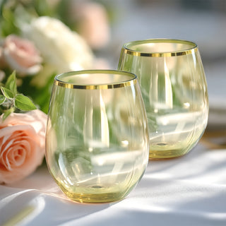 Elegant gold-rimmed stemless glasses on a table with floral accents.