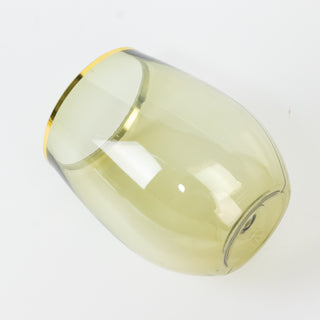 Green glass tumbler with gold rim, angled view.