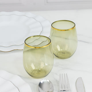 Two elegant stemless glasses with gold rims on a marble table.