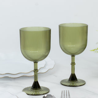Green ribbed glassware set on white marble background.