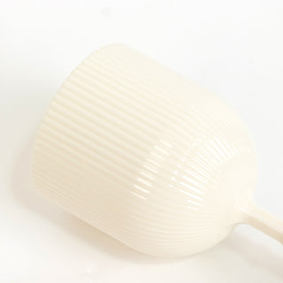 Cream ribbed ceramic cup on a plain backdrop