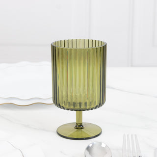 Green ribbed glass on a marble surface with utensils.