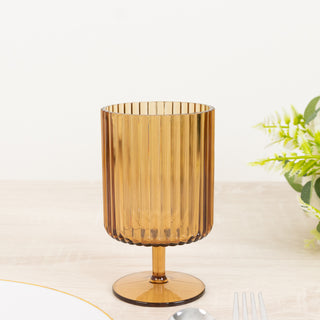 Amber ribbed glass cup on a wooden table with a floral accent.