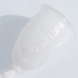 White ornate cup with embossed design on a plain white background
