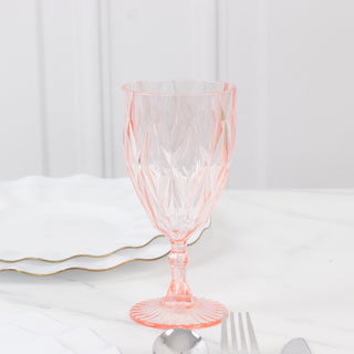 Pink crystal wine glass on a marble table with white plates and silverware.