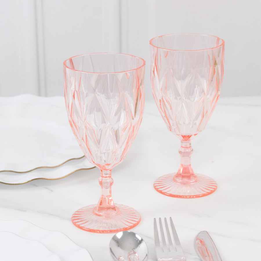 Two elegant pink crystal goblets on a marble table setting.