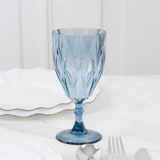 Blue crystal goblet with diamond pattern on a white tabletop.