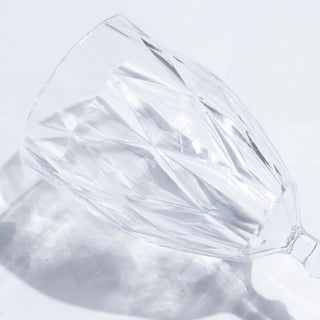 Crystal wine glass with a diamond cut design on a plain background