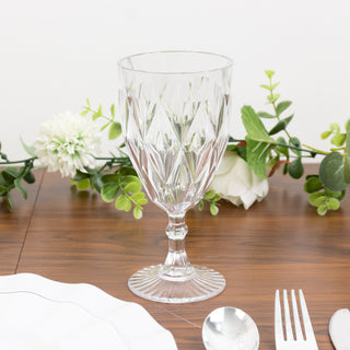 Crystal wine glass on a wooden table with decorative greenery.