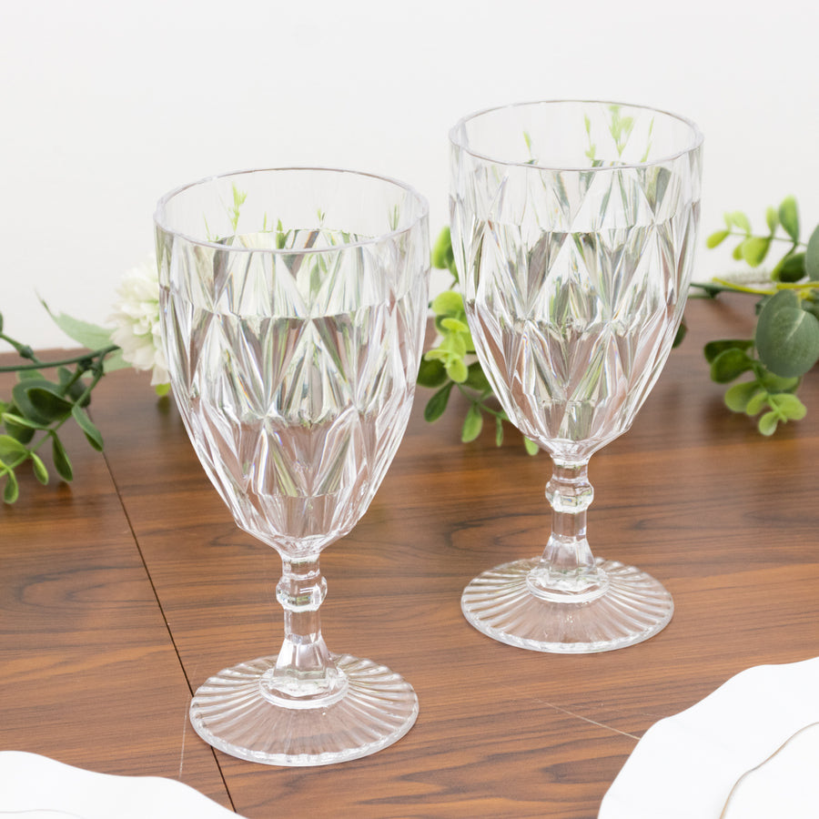 Elegant crystal goblets on a wooden table with greenery.