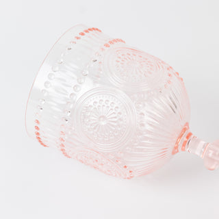 Pink decorative glass with intricate pattern and raised dots, angled view.