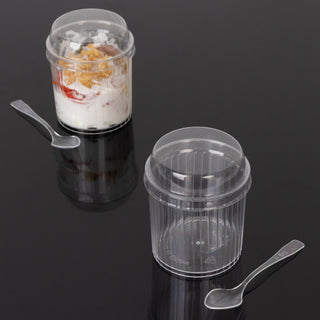 Clear plastic dessert cups with spoons on a black surface.