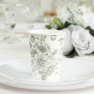 Floral design paper cup on a white plate with decorative background elements.