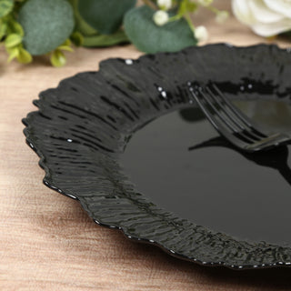 Black decorative plate with textured edges and a fork on a wooden surface.